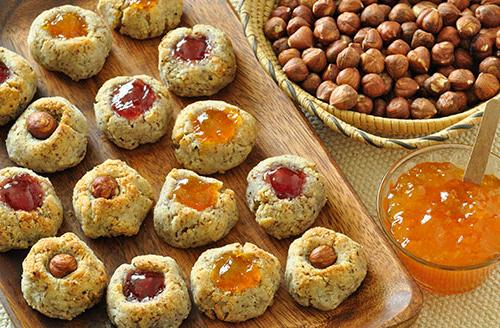 hazelnuts next to tray of hazelnut cookies with a jar of jam